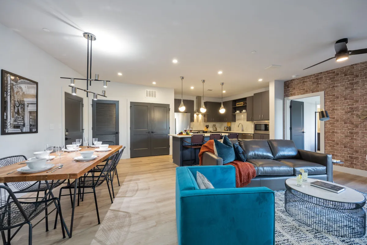 A multifaceted living area that blends a kitchen island, dining table, comfortable sofa, and eye-catching wall art. The scene suggests active moments—dining, socializing, and cooking—all within a welcoming atmosphere.