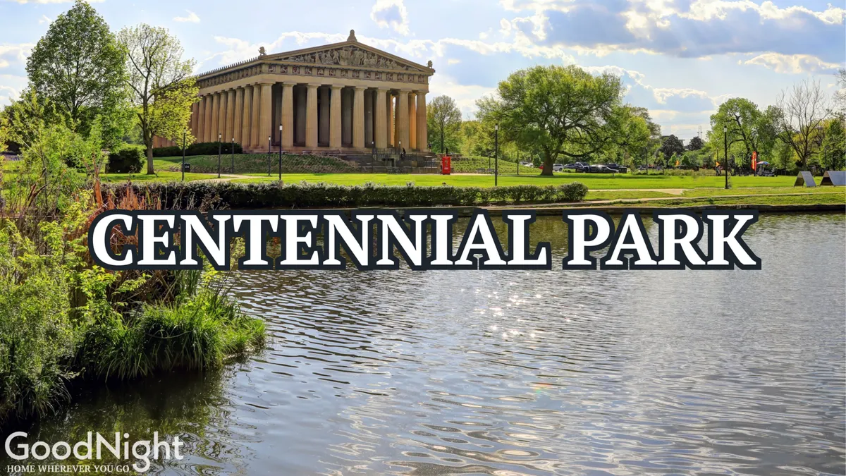 A scenic view of the Parthenon-like building in Centennial Park, set alongside calm lake waters, surrounded by lush green grass and mature trees. The foreground shows inviting lawns and the serene water, while the background features the iconic Athenian-inspired structure, hinting at art events and family-friendly park activities.